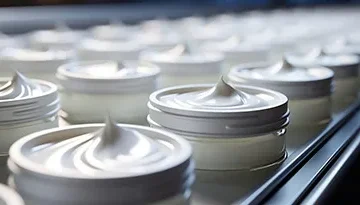 A photo of cosmetic cream on a conveyor belt